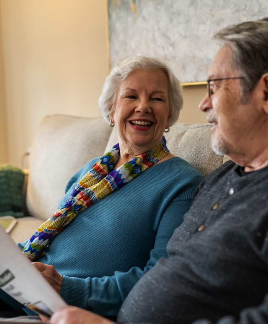 A man and a woman sharing a smile on their couch