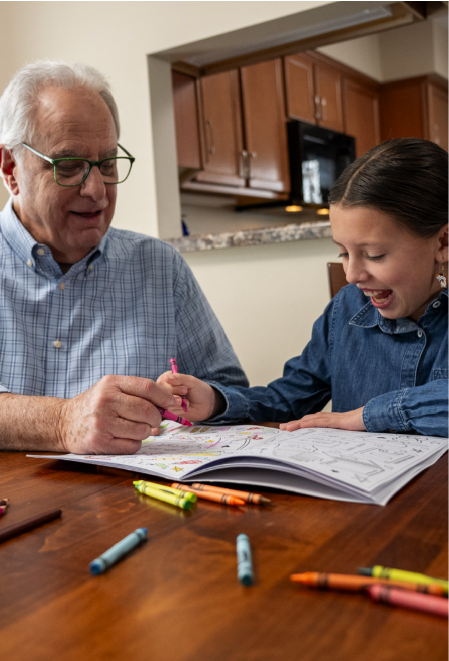 A man and his granddaughter coloring together